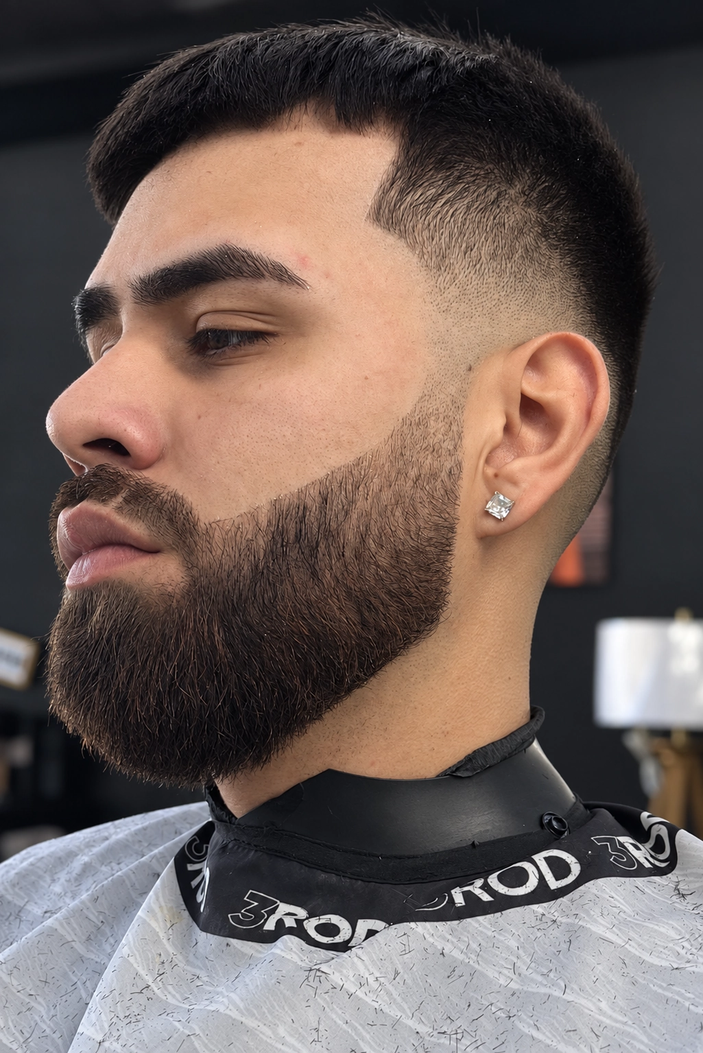 Client in profile with a high fade and a sculpted beard
